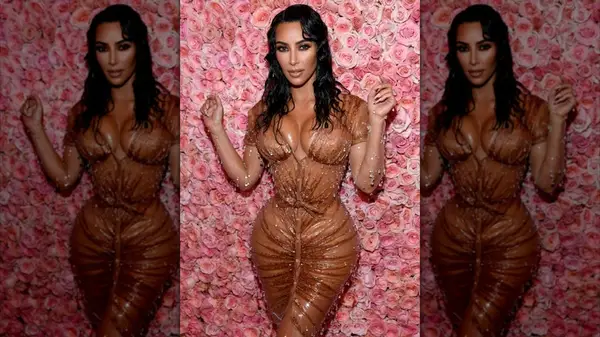 Kim Kardashian in front of a rose wall in a brown, wet dress
