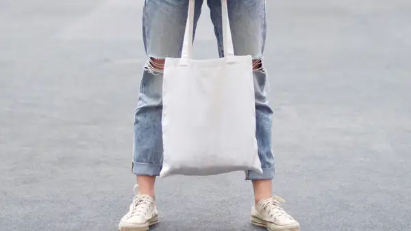 person holding white tote bag