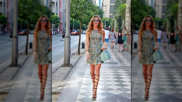 A woman walking toward the camera in a floral mini dress and sandals laced up to the knee