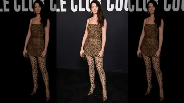 Anne Hathaway posing in a cheetah-print mini dress and matching tights at a Valentino Haute Couture show