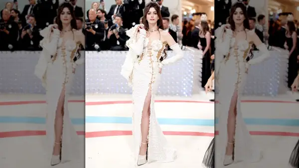 Anne Hathway posing in a tweed dress with a high slit at the 2023 Met Gala