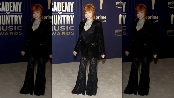 Reba McEntire looking off-camera while wearing a sequined jacket, lace and fringe pants, and a topaz necklace