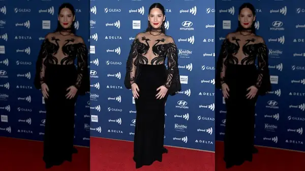 Olivia Munn smiling while wearing a gown with peacock silhouettes on the sheer bodice