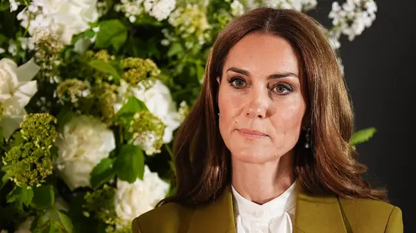A headshot of Kate Middleton in front of an arrangement of flowers
