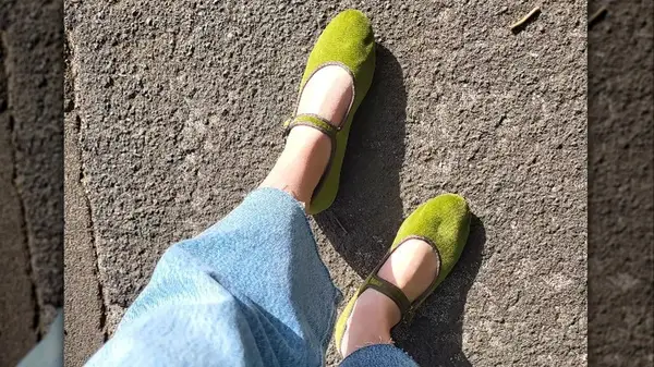 Closeup of feet on pavement wearing green mary janes