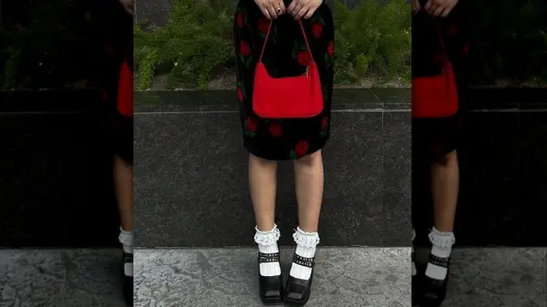 Closeup of person holding red purse wearing floral dress