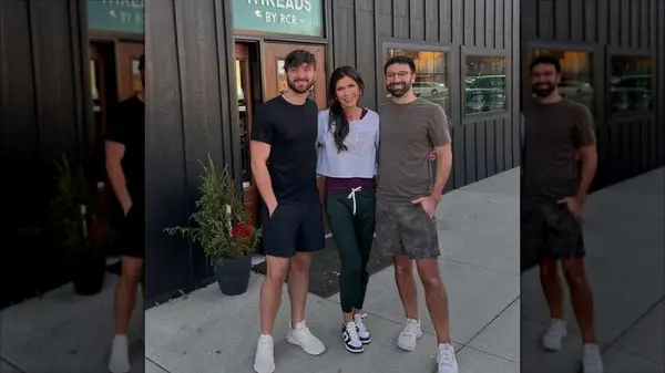 Kristi Noem posing with two men in sweatpants and a cropped sweater