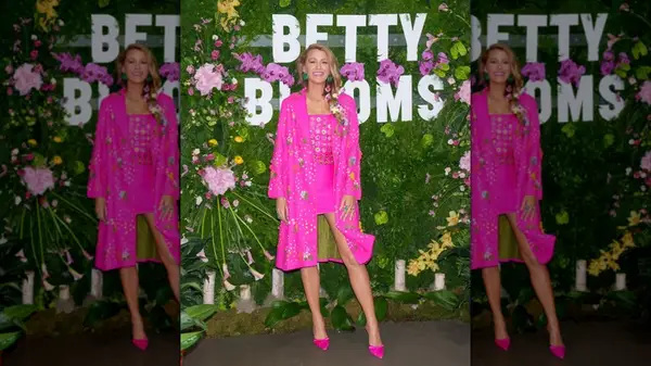 Blake Lively in front of a floral step and repeat in an matching hot pink dress and jacket set