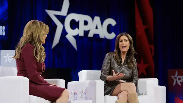 Sarah Huckabee Sanders on stage at CPAC in a brown leather dress