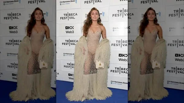 Miley Cyrus waving in an open-weave knit dress with enormous fringe shawl