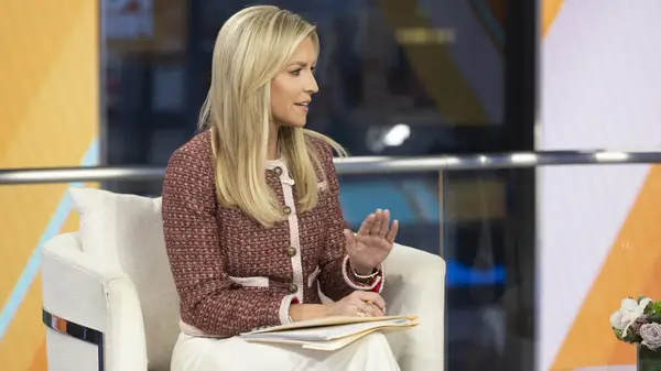 Ainsley Earhardt wearing a cropped boucle jacket on a stage while raising her hand