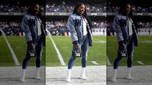 Simone Biles smiling at an NFL game while wearing skinny jeans and a denim jacket