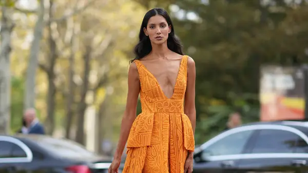 Fashion week guest wears tangerine orange dress