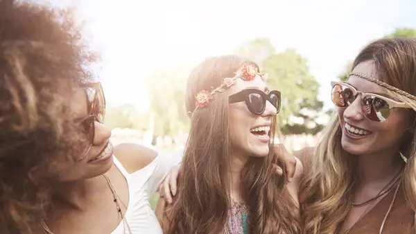 Three women stand together smiling, two wearing different kinds of headbands
