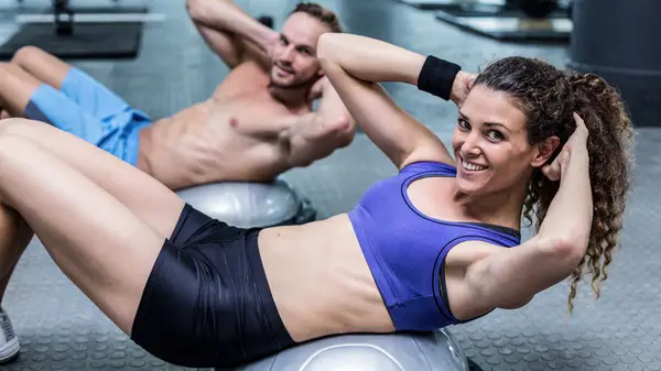 Man and woman doing crunches on Bosu ball 