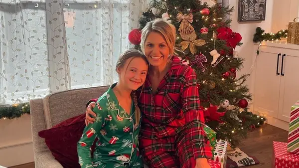 Candace Cameron Bure and her daughter dressed in pajamas in front of a Christmas tree
