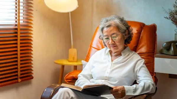 Older lady reading while sitting in a chair