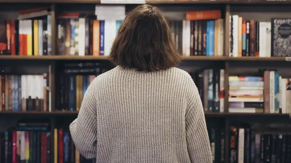 Short-haired woman facing bookstore shelves