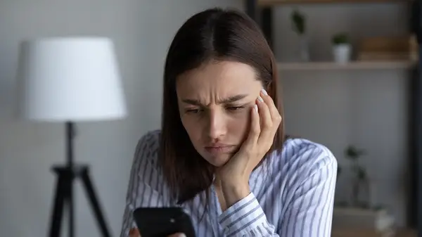 woman anxiously stares at phone