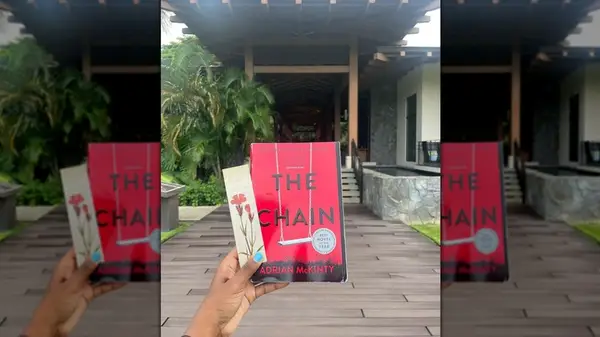 A hand holding a copy of the novel 