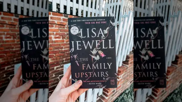 A hand holding a copy of the novel 