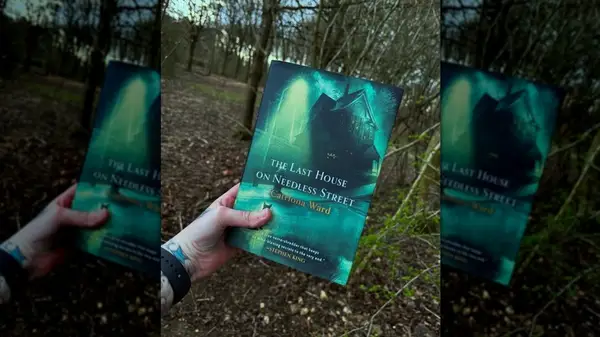 A hand holding a copy of the novel 