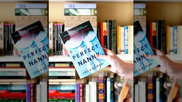 A hand holding a copy of the novel 