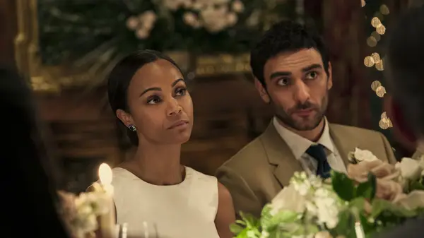 Zoe Saldana and Eugenio Mastrandrea sitting at a dinner table
