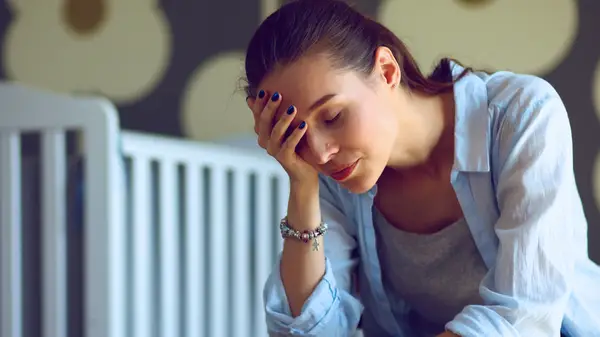 Tired mother next to a crib 