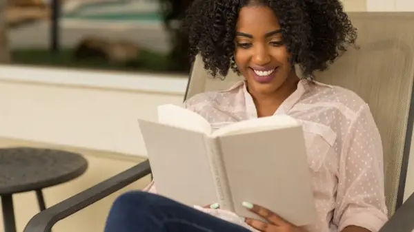 A woman smiling and reading a book