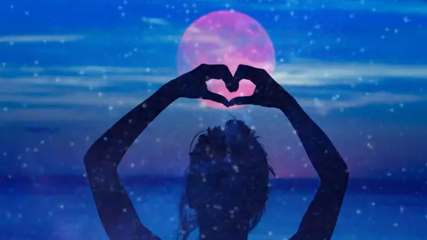 woman making heart over moon