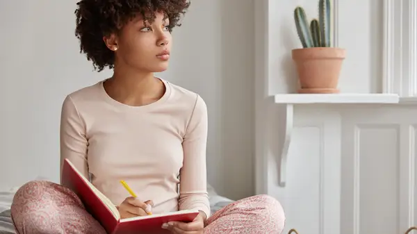 woman journaling on bed