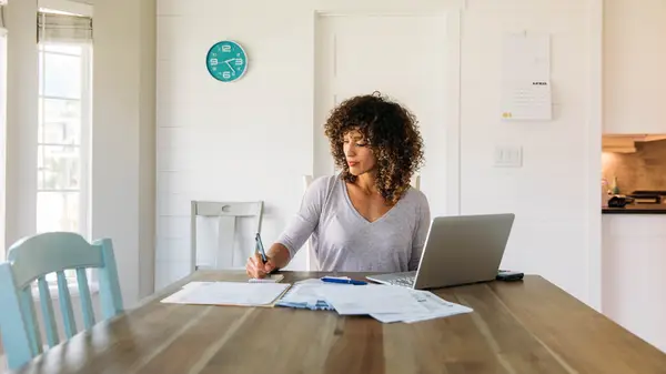 Woman paying bills at dining room table