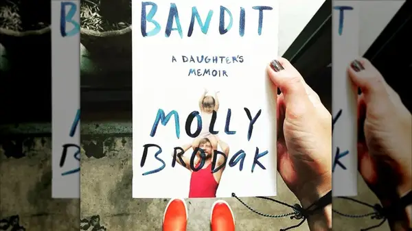 A hand holding up a copy of the book 