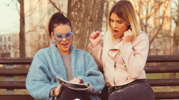 Girls on bench reading horoscopes