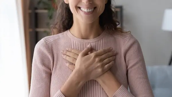 Woman holds hands over her heart