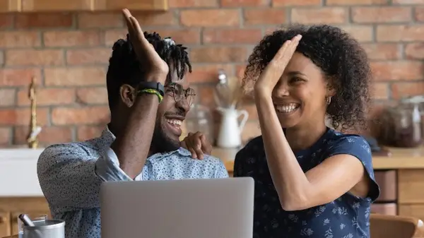 Couple high-fiving by laptop