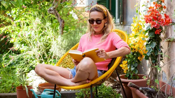 A woman sits outside and reads a book