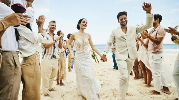 A bride and groom walking down a line of wedding guests
