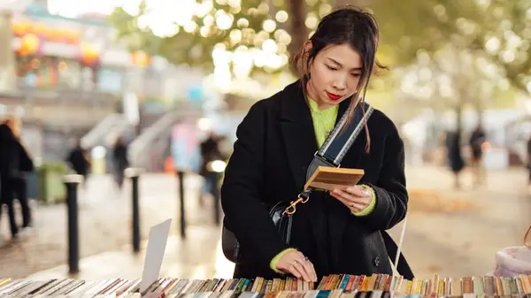 Woman browsing used books in an outdoor setting