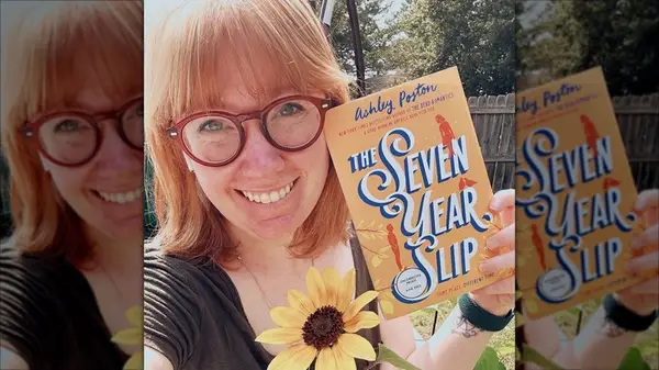 Ashley Poston smiling for a selfie while holding up 