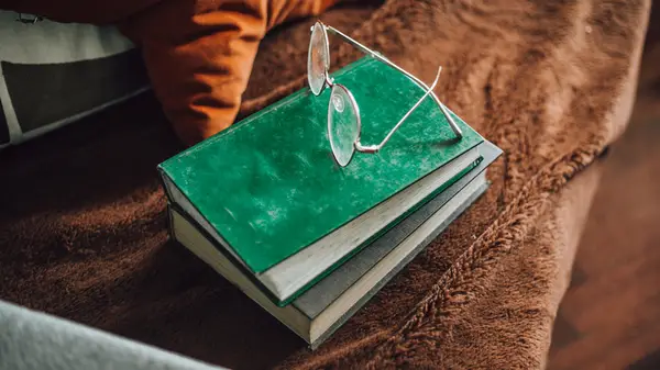 A stack of two books and glasses on a fluffy brown blanket