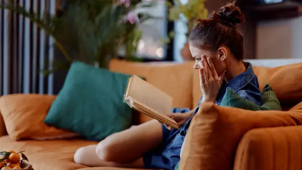 A woman reading a book on a sofa