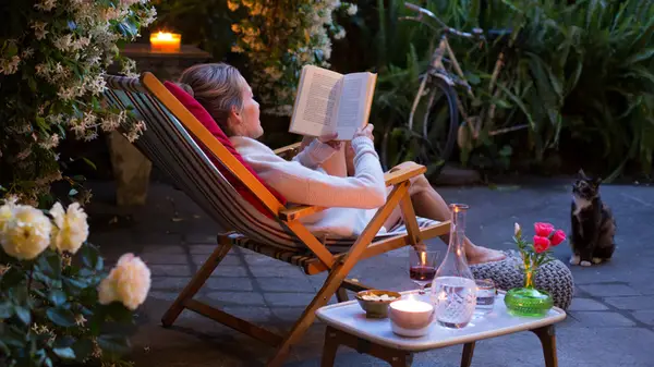 A woman sitting outside at dusk reading a book
