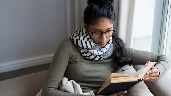 Woman sitting comfortably on the couch and reading a book