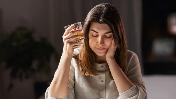 unhappy woman with glass of alcohol