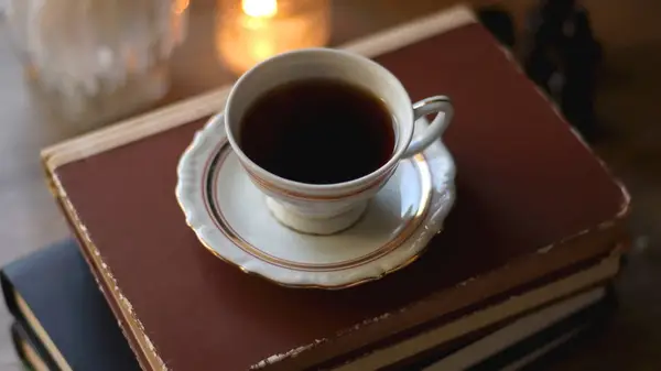 A cup of tea sitting on top of a stack of old books