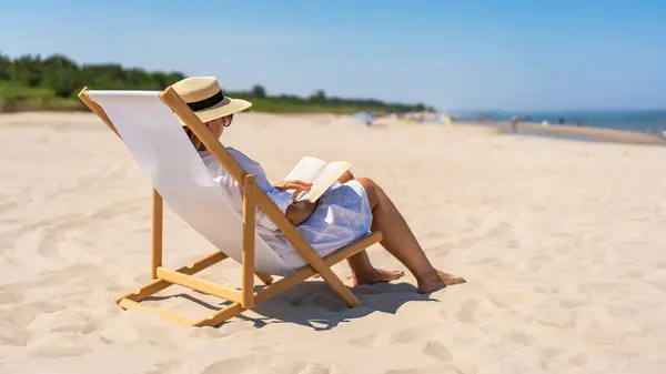 A woman reads peacefully on the beach
