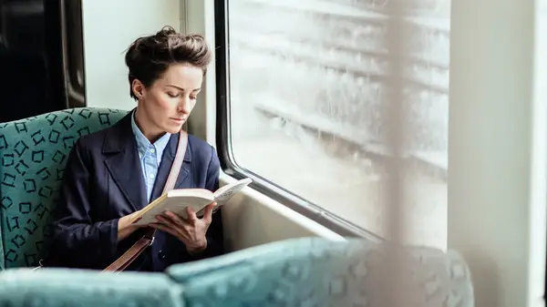 A woman reads a book sitting in a train