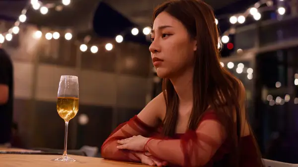woman frowning with drink at table